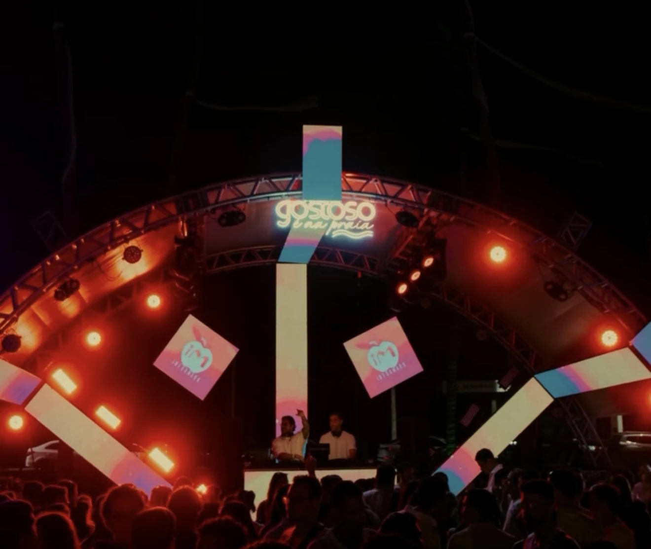 Palco iluminado com público durante edição anterior do festival